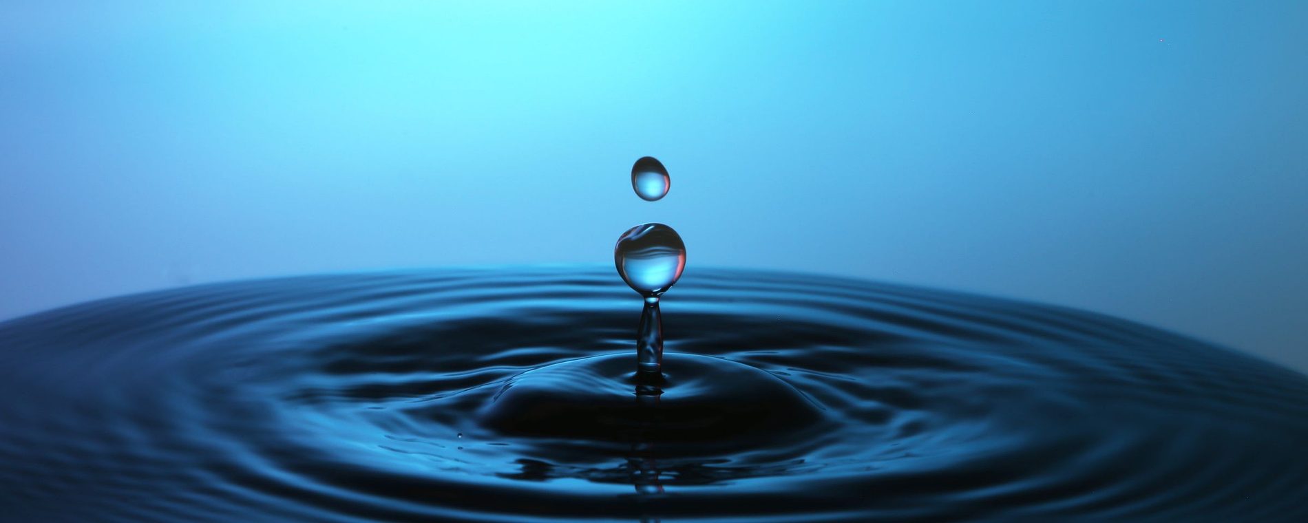 A droplet meeting still blue water